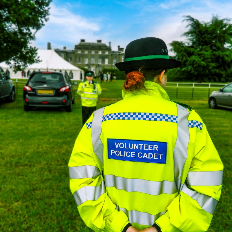 Photograph of the back of a volunteer cadet stood in a field at an event