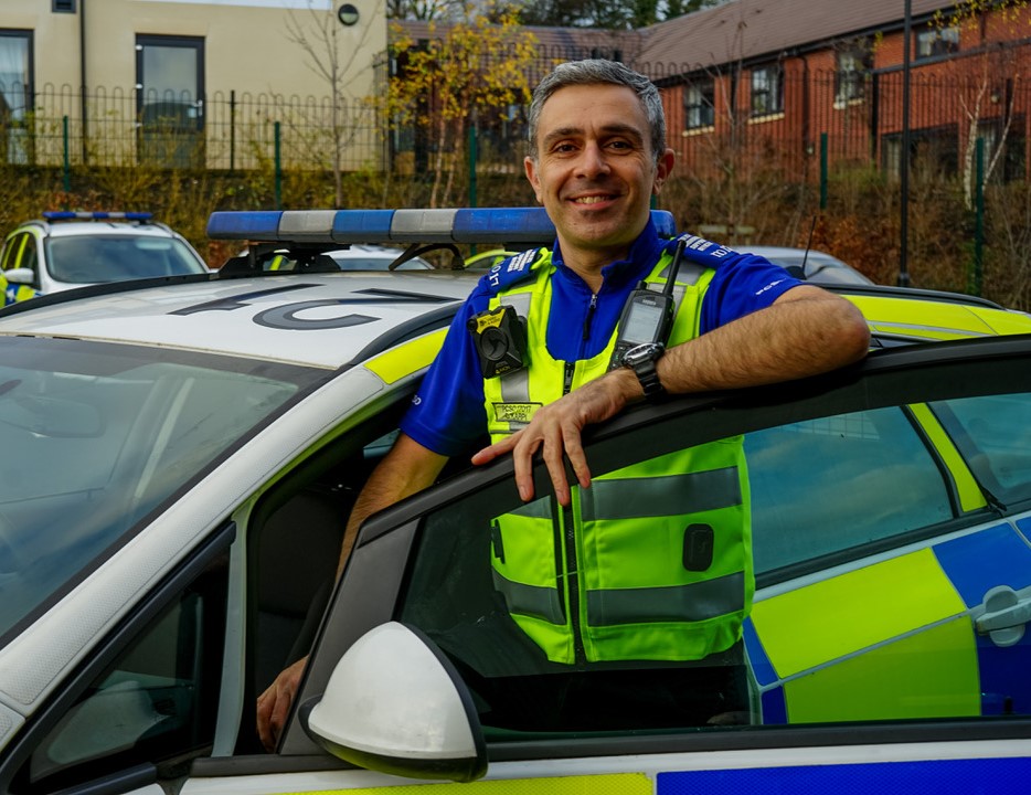 Smiling male police officer getting into police car