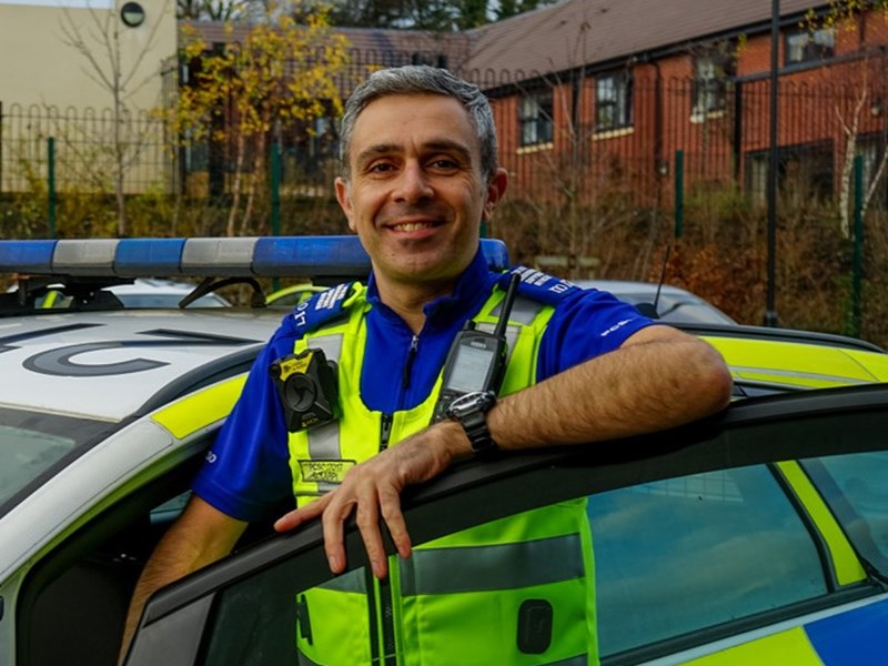 Smiling male police officer getting into police car