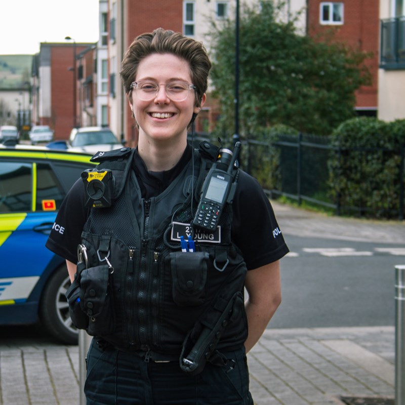 Smiling female police officer in front of a police car