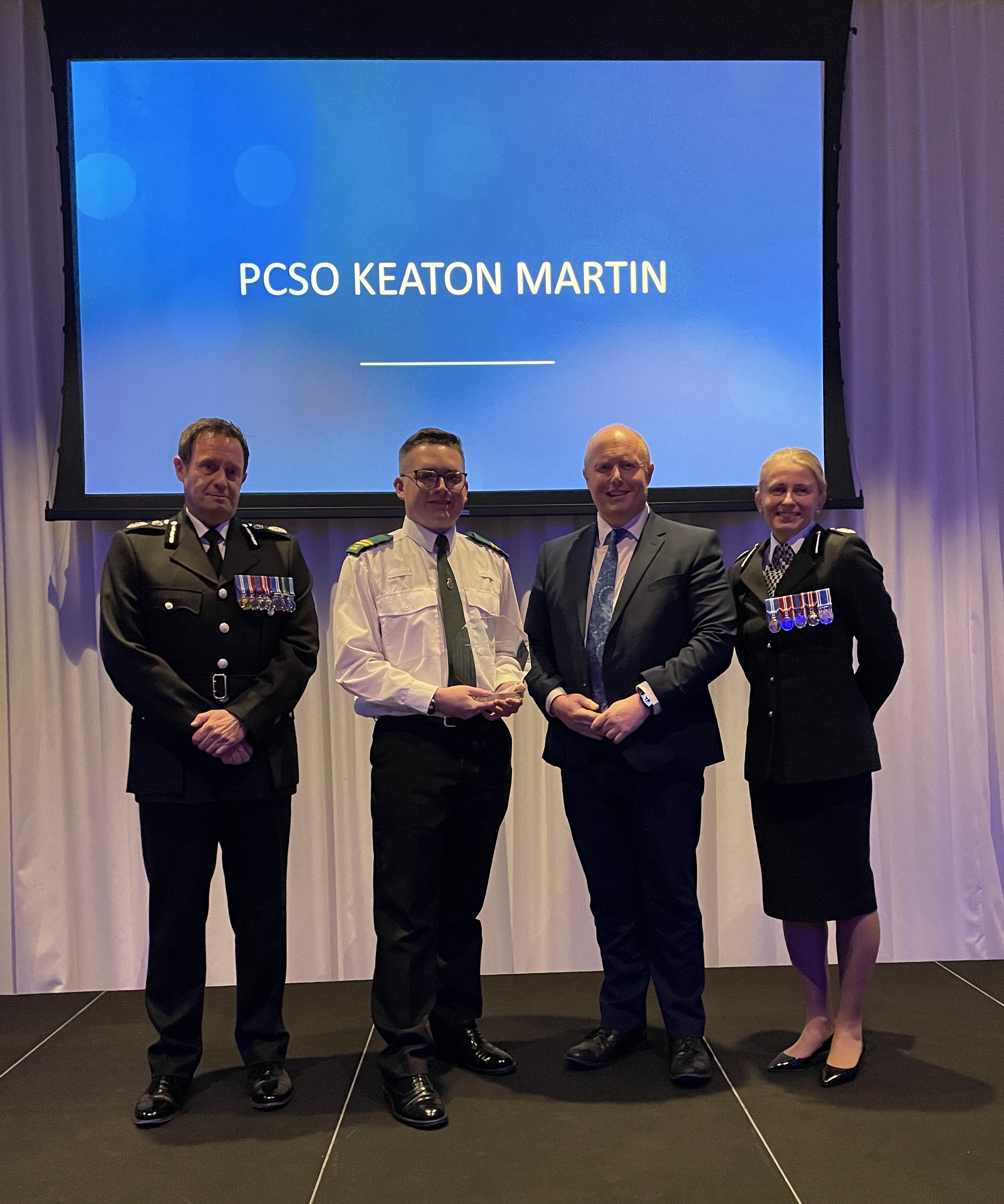 Chief Constable, Chris Noble stood with ACC Becky Riggs and award winner Keaton Martin at the 2024 Force Awards where Keaton is accepting his Volunteer of the Year award